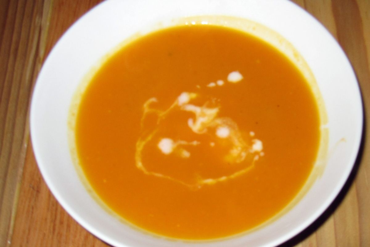 Bowl of smooth orange butternut squash soup with a swirl of cream