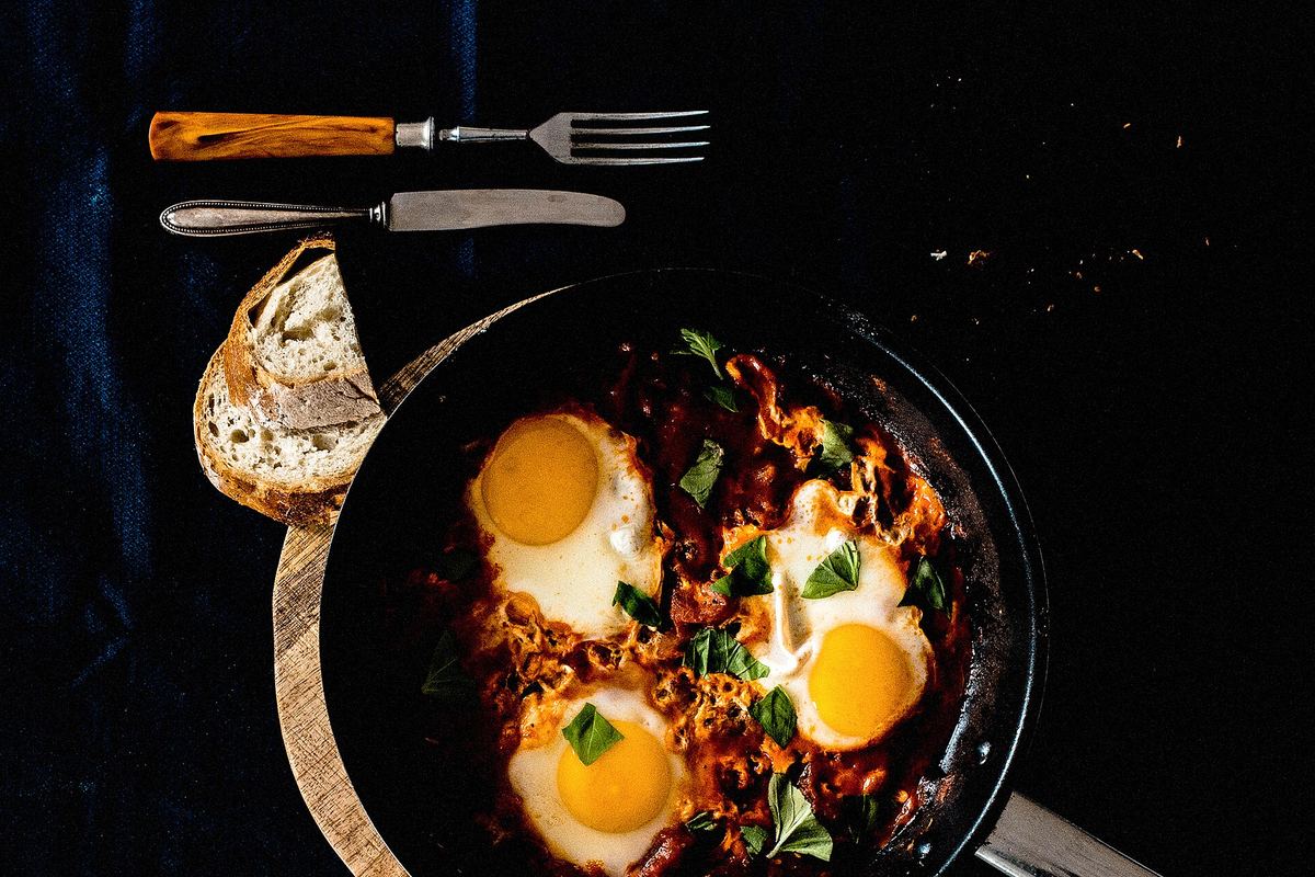 Skillet of shakshuka with eggs cooked in tomato and pepper sauce