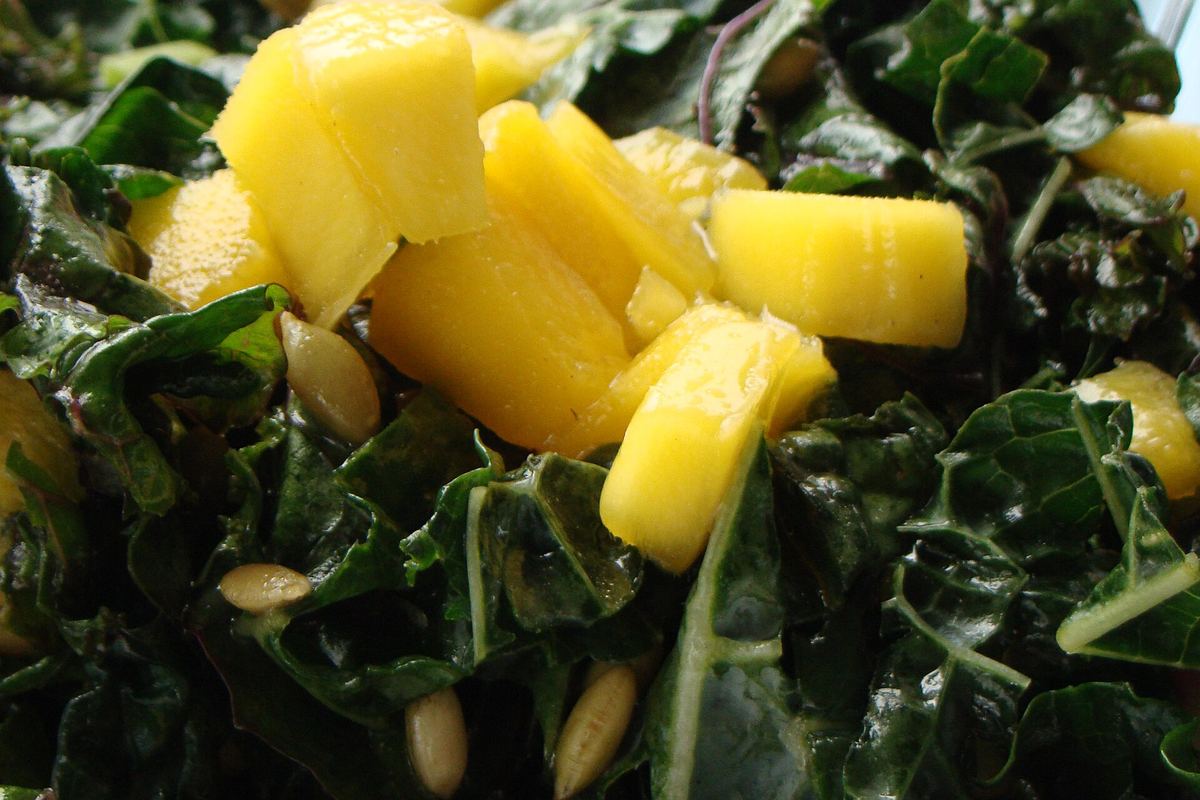 Close-up of a massaged kale salad with chopped fruit and seeds