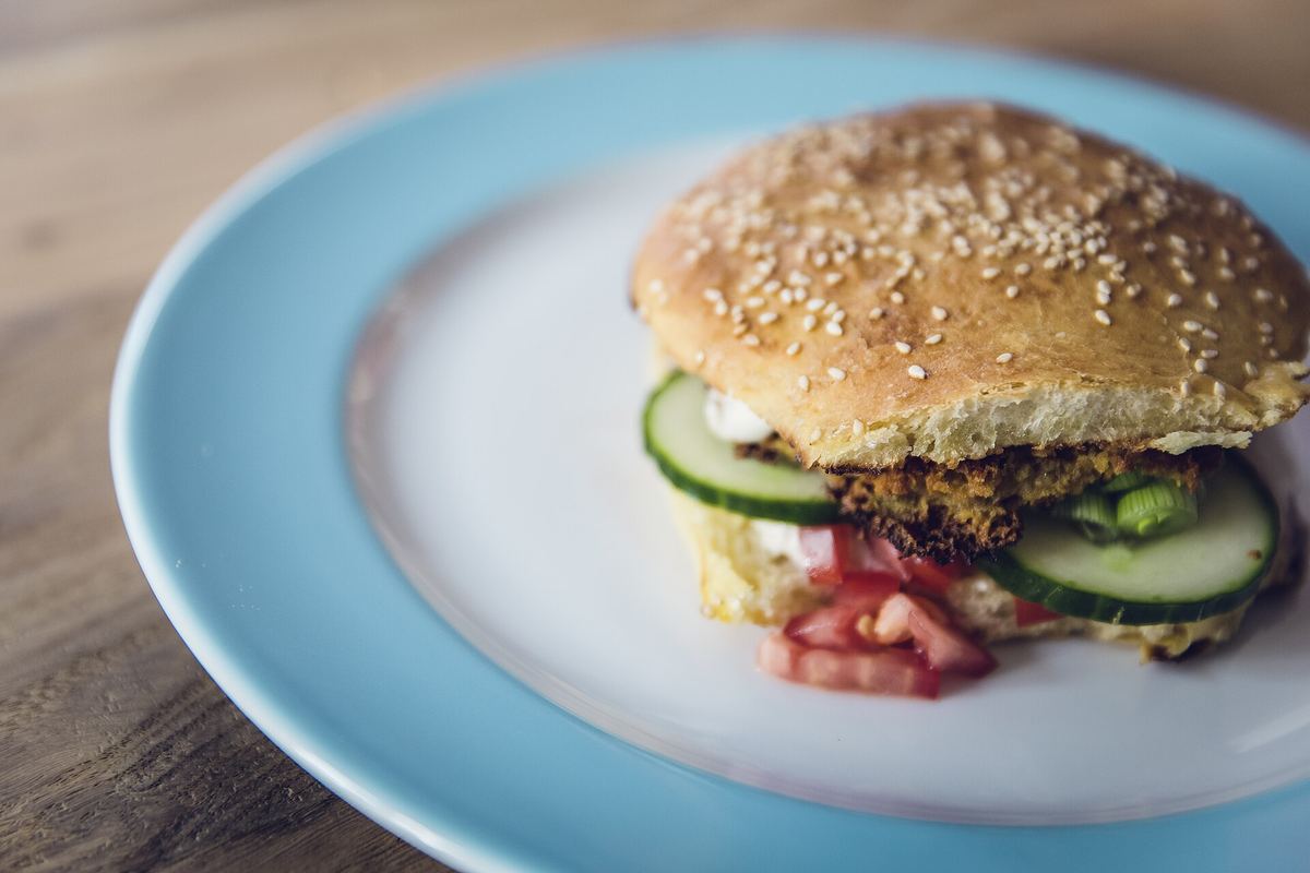 Veggie burger with lettuce, cucumber, and red onion on a blue plate