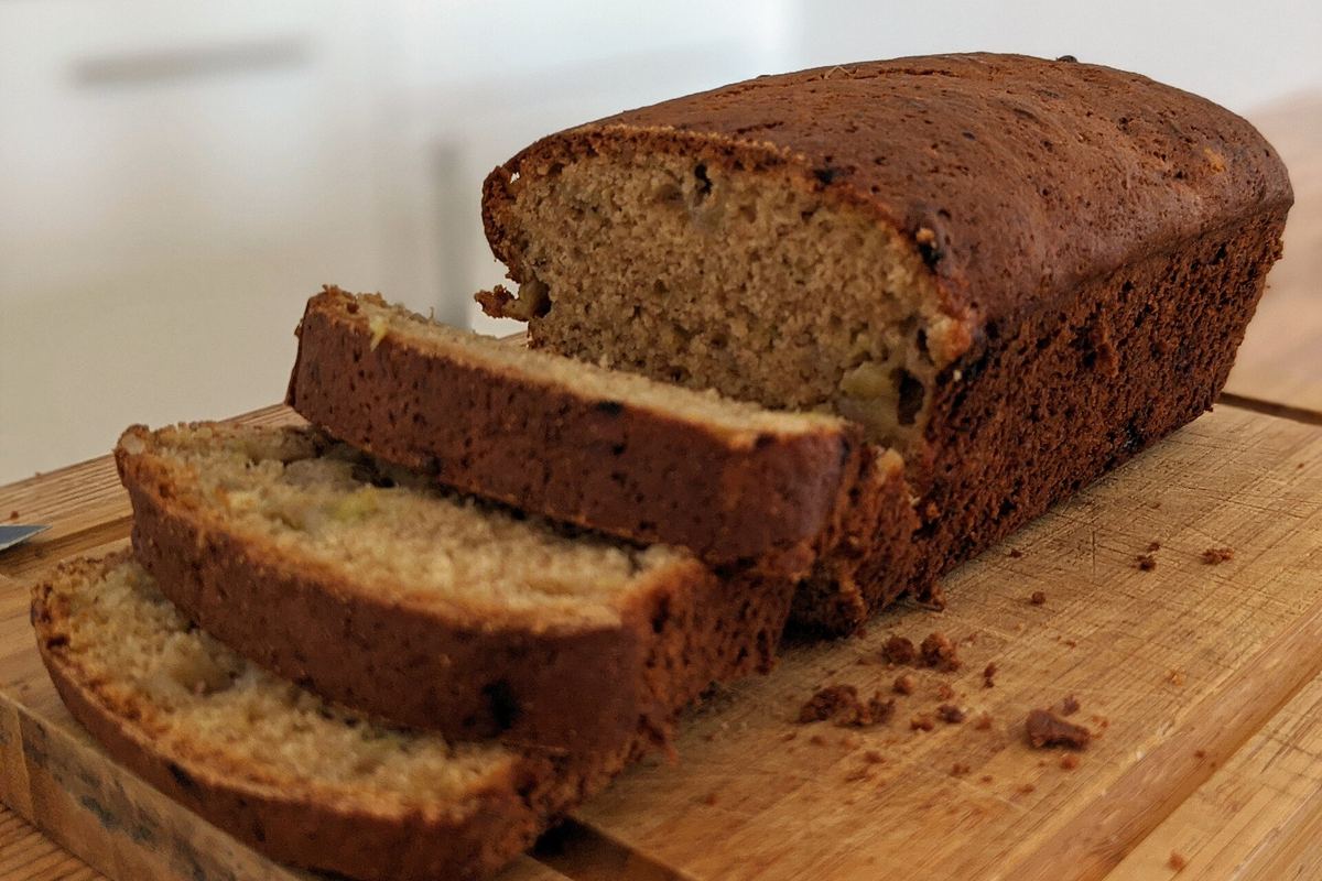 Loaf of banana bread cut into slices on a wooden board
